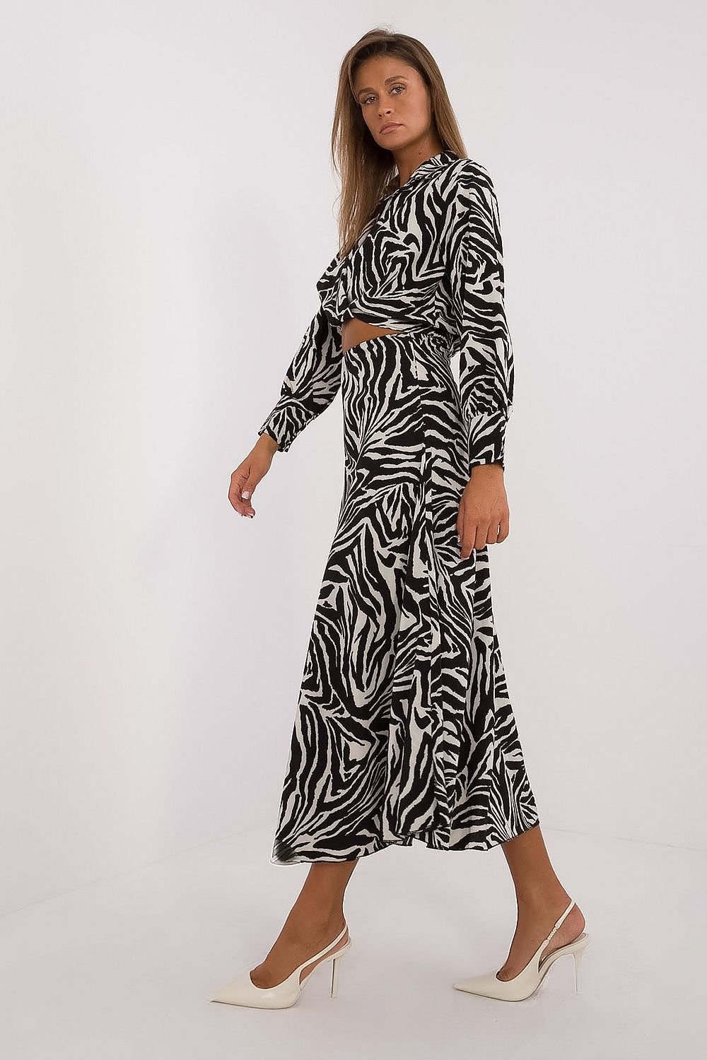 Een vrouw draagt een elegante, zwart-witte jurk met een opvallend zebrapatroon en een wikkelmodel bovenstuk met lange mouwen.zj uitzicht