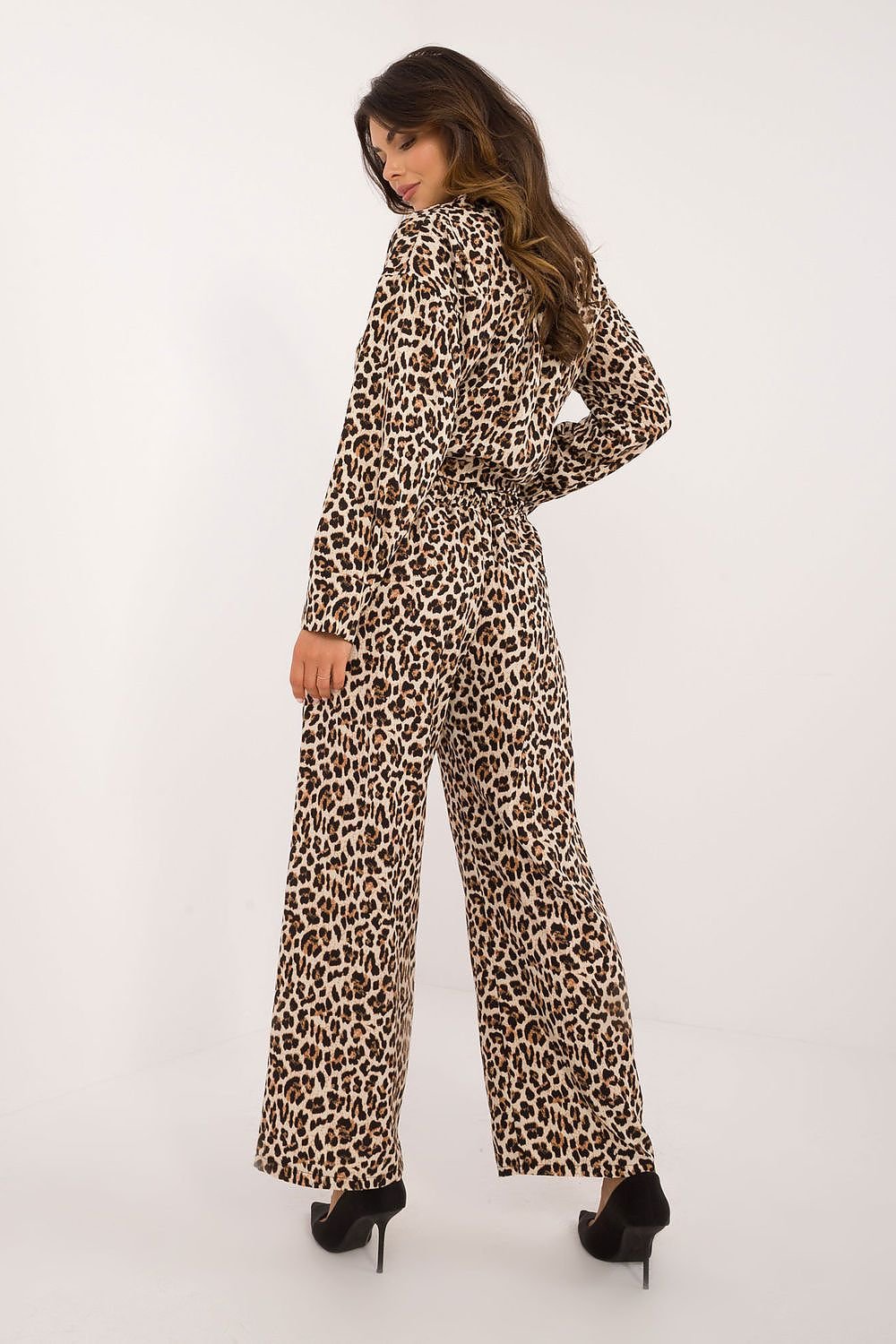 Een vrouw draagt een modieuze co-ord set met luipaardprint, bestaande uit een geknoopte blouse met lange mouwen en een wijde broek,achter uitzicht