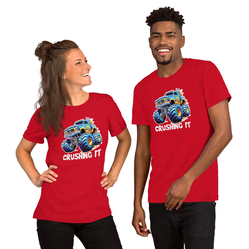 Een zwart unisex T-shirt met een afbeelding van een monstertruck, vooruit kijkend, met een lachende man en vrouw, op een witte achtergrond.