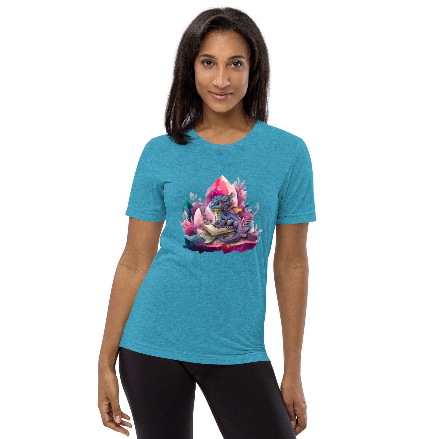 Een aqua triblend unisex T-shirt met een afbeelding van een kleine draak en een magisch boek, gedragen door een blije vrouw, op een witte achtergrond. De vrouw staat naar voren gericht.