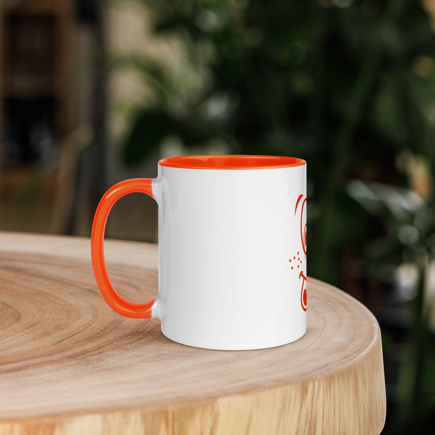 Een witte keramieken mok met een vrolijke cartoonafbeelding. De binnenkant van de mok is oranje. Het betreft een vooraanzicht van een mok van 11 oz, waarbij de afbeelding aan de rechtervoorkant staat. De mok staat op een houten ronde tafel met de handgreep aan de linksvoorkant