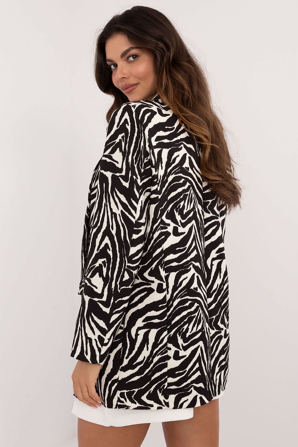 Een blije vrouw draagt een elegant gevoerd damesjack met luxe dierenprint, zwarte blouse en witte mini rok, 