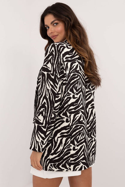 Een blije vrouw draagt een elegant gevoerd damesjack met luxe dierenprint, zwarte blouse en witte mini rok, 