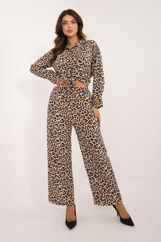 Een vrouw draagt een modieuze co-ord set met luipaardprint, bestaande uit een geknoopte blouse met lange mouwen en een wijde broek, voor uitzicht