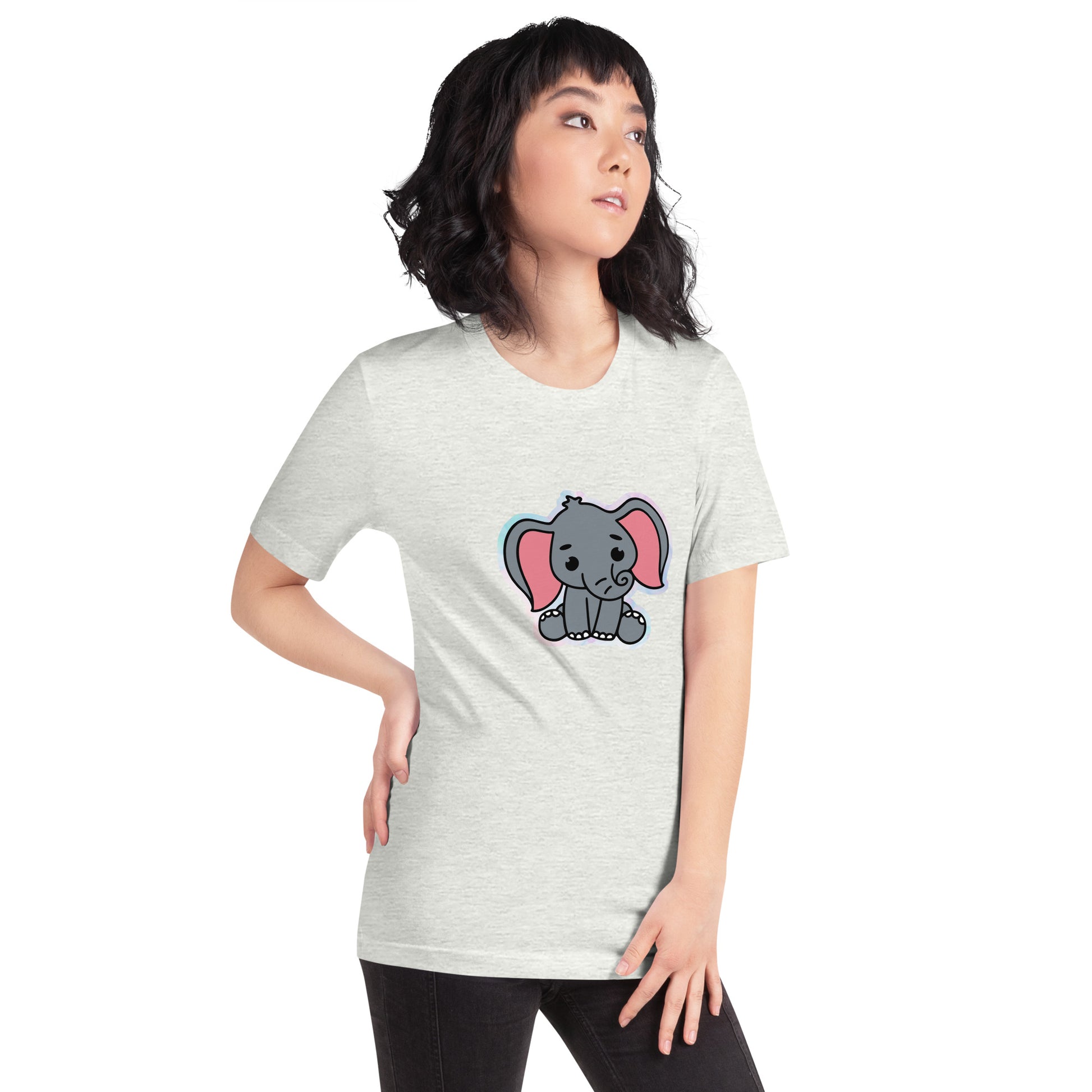 Een ash kleurige unisex T-shirt met een afbeelding van een grappige grijze baby olifant, gedragen door een vrouw, aan de rechtsvoort op een witte achtergrond.