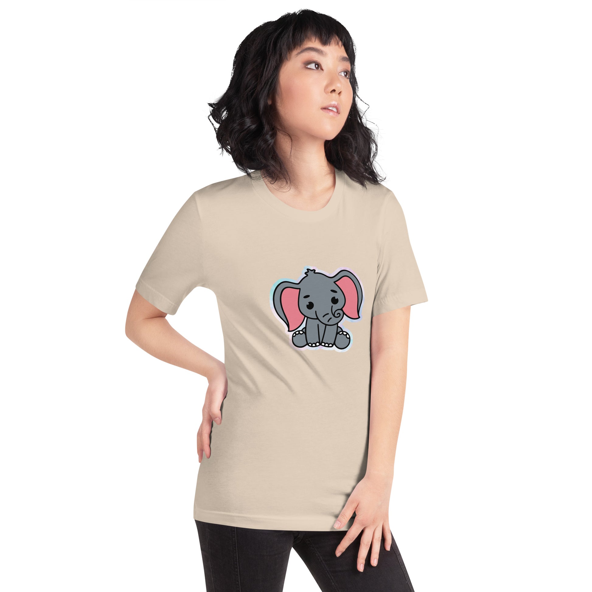 Een crèmekleurig unisex T-shirt met een afbeelding van een grappige grijze baby olifant, gedragen door een vrouw, aan de rechtsvoort op een witte achtergrond.